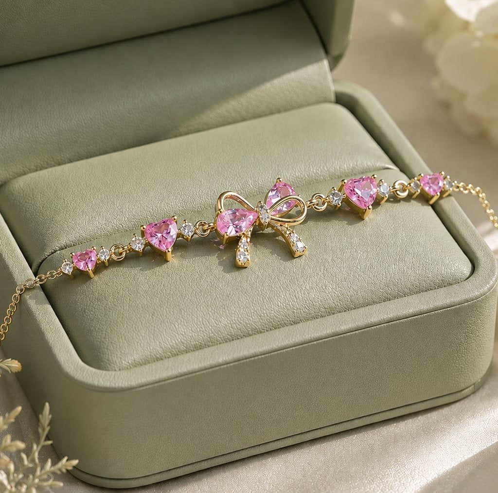 FairyLiora Bow Bracelet in gold with pink heart cubic zirconia stones, presented in a sage green gift box