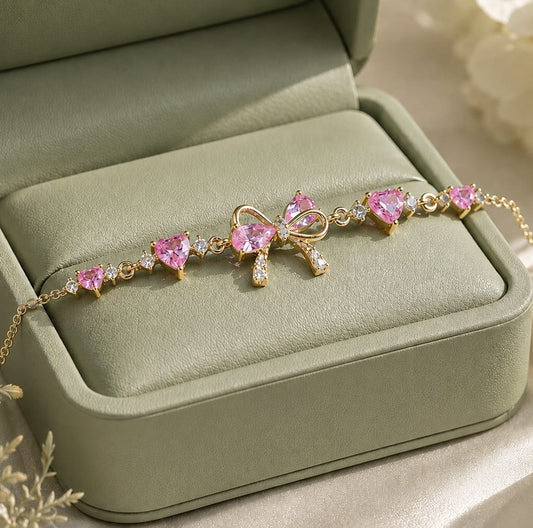 FairyLiora Bow Bracelet in gold with pink heart cubic zirconia stones, presented in a sage green gift box