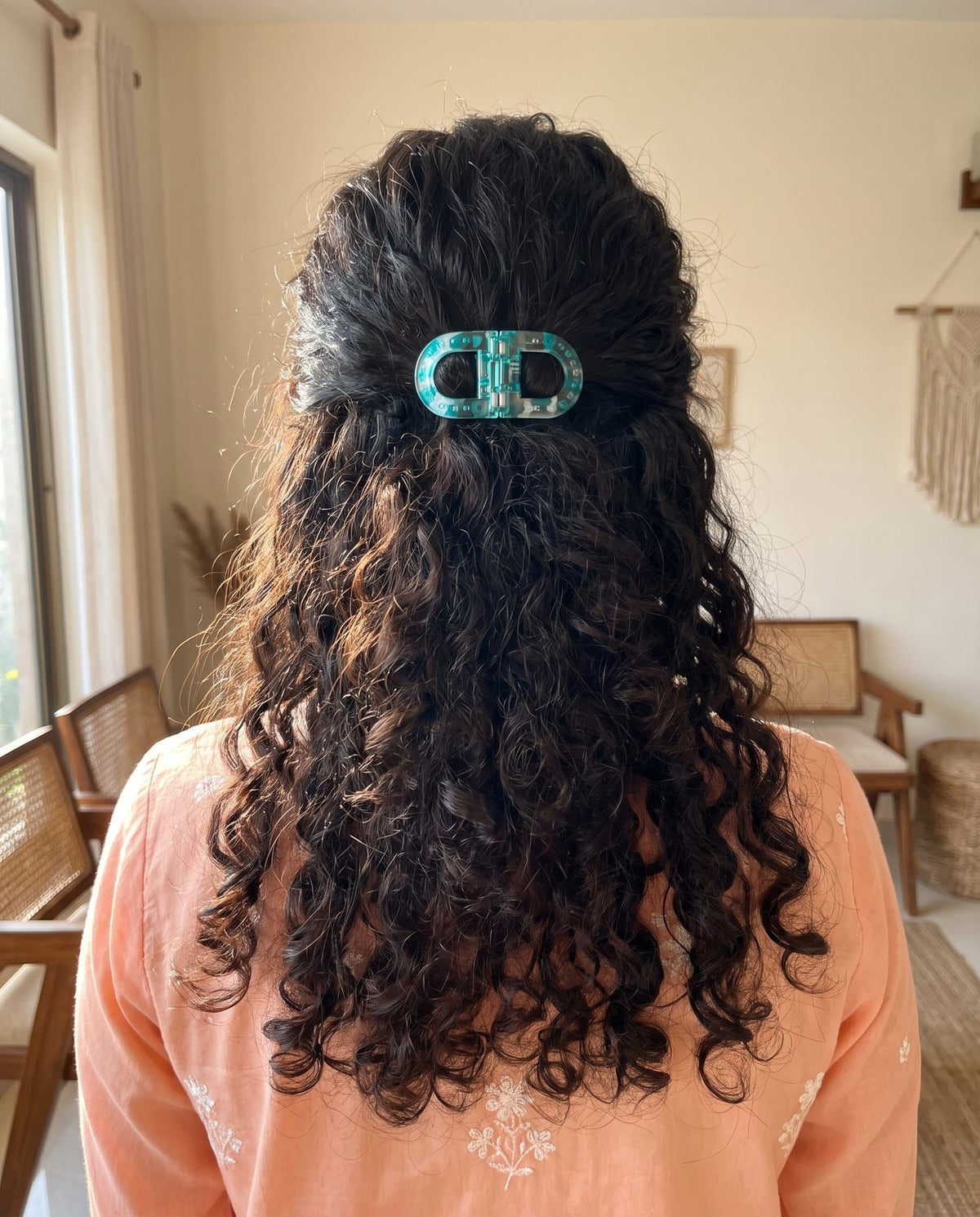 Turquoise clip holding a half-up in dark curly hair, peach kurta